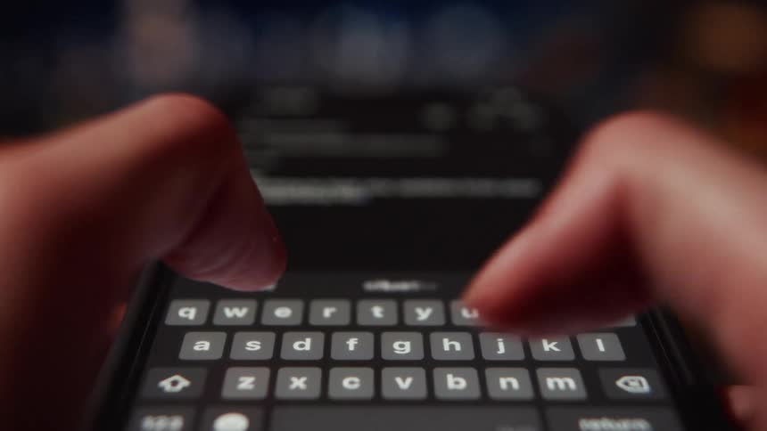 Extreme close-up macro shot of fingers quickly typing a message on a smartphone keyboard