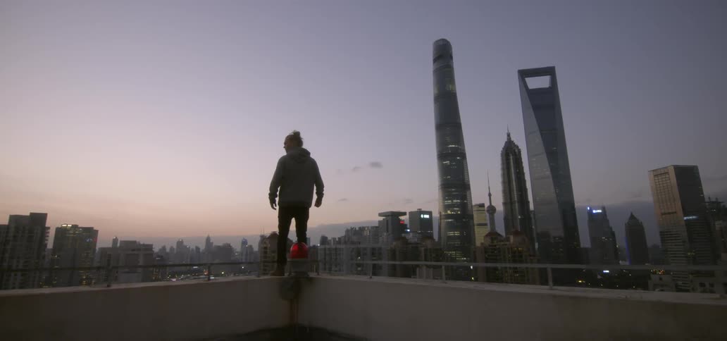 A man leans over the edge of a roof