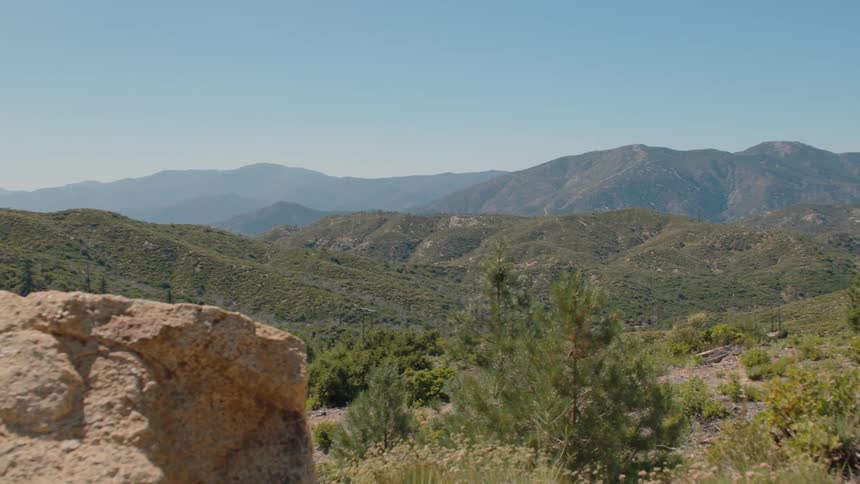 An expansive view of a verdant mountain range under a clear blue sky on a sunny day