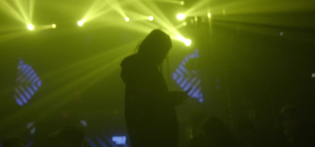 A person is standing in a club checking their phone