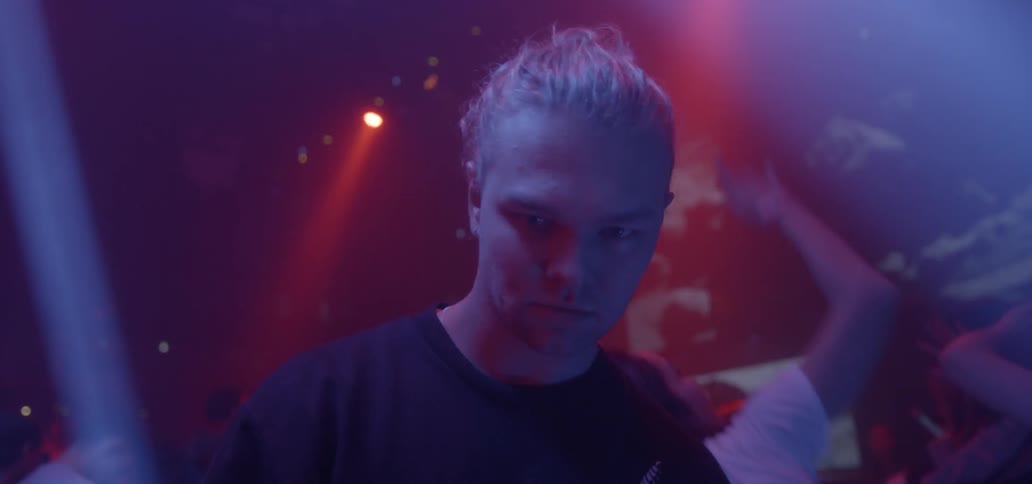 A man stands in a nightclub with flashing lights