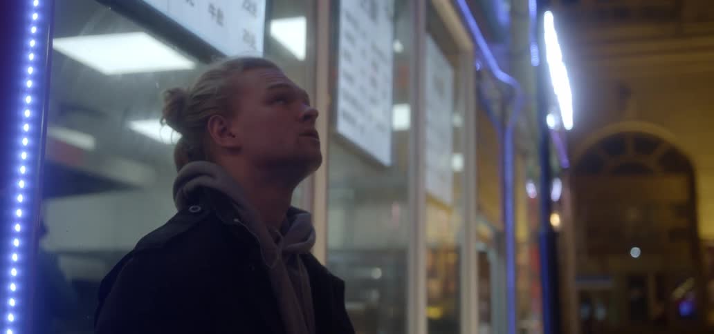 A man leans against a shop window at night