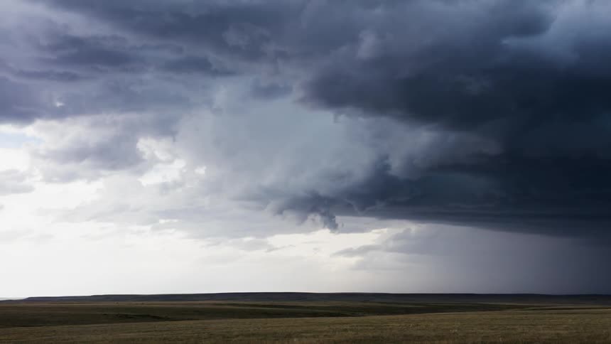 Storm clouds swirl over an open field