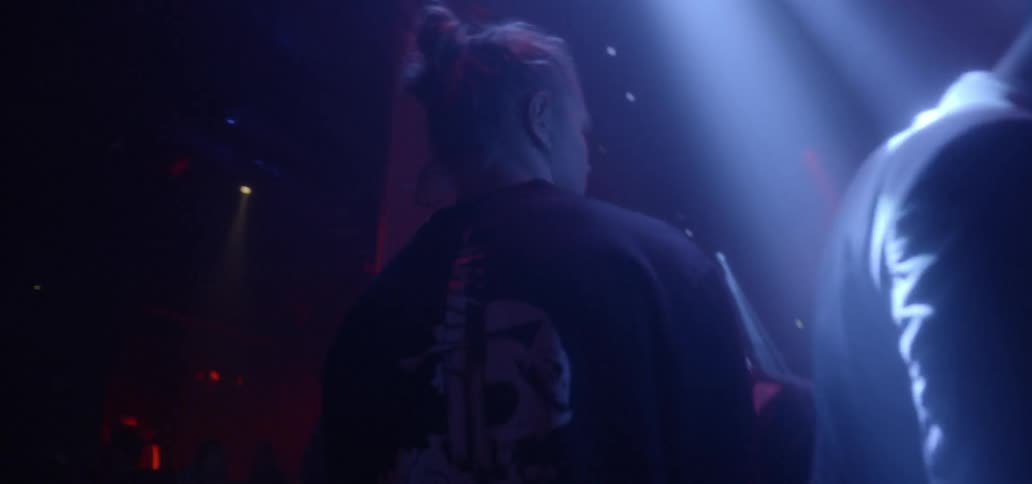 A man walks beneath, flashing colored lights through a crowded club
