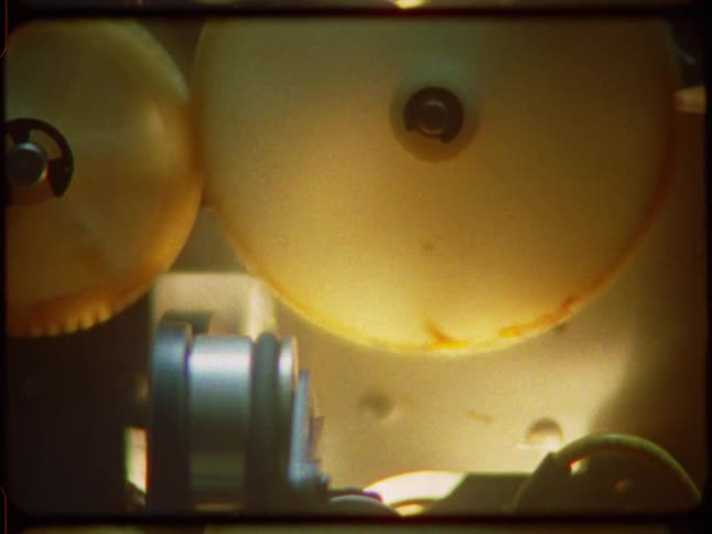 Super 8mm film captures a close-up, abstract view of spinning plastic gears inside a vintage machine