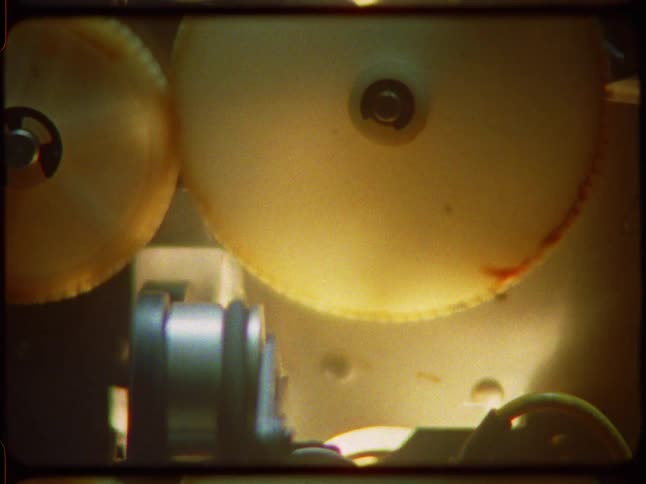 Close-up of the internal plastic gears of a vintage film projector turning continuously