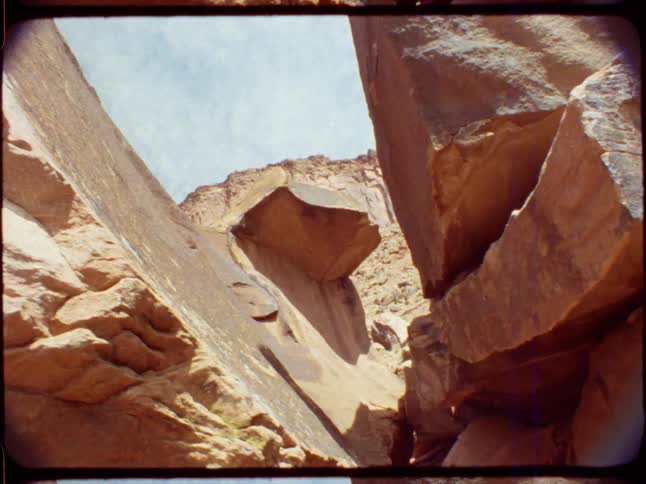 Archival 8mm footage showcases the dramatic red rock formations and steep cliffs of a desert canyon