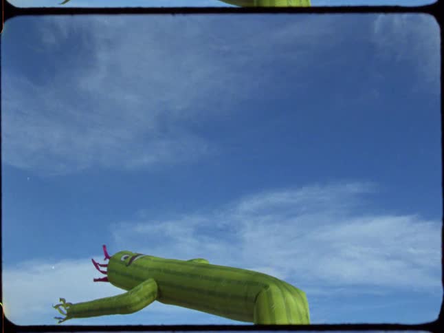 A wacky waving inflatable cactus man dances and flails erratically against a clear blue sky in this vintage-style footage