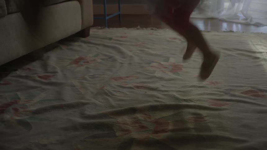 A person and child jump on the rug together