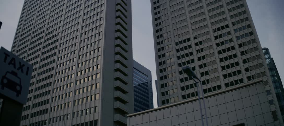 A slow revealing shot of imposing modern skyscrapers in an urban financial district, starting from a taxi sign