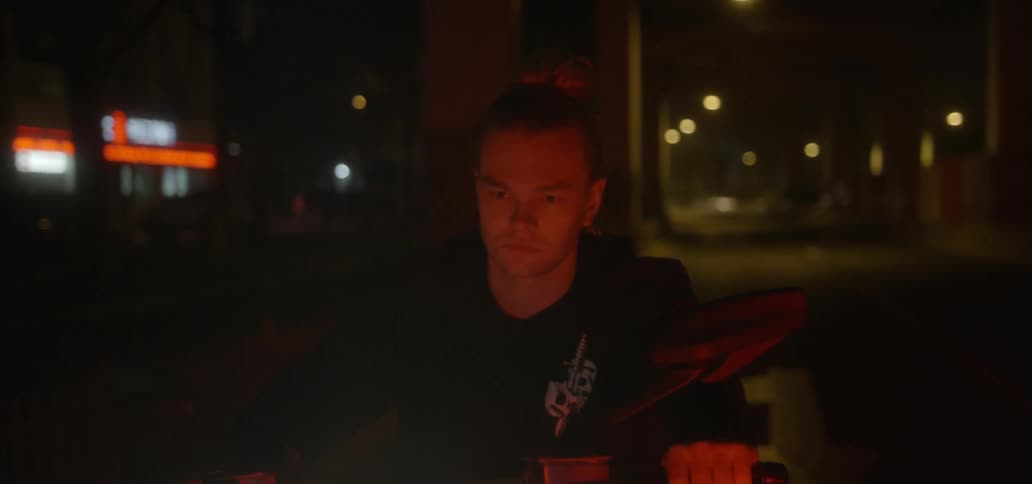 A young man riding a motorcycle at night in an urban setting