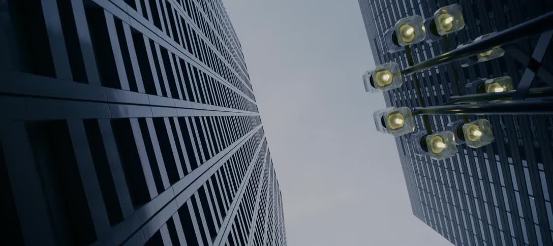 A low-angle, cinematic pull-back shot reveals the immense scale of two modern skyscrapers against an overcast sky