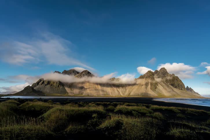 Clouds float around rocky mountains as a rainbow disappears