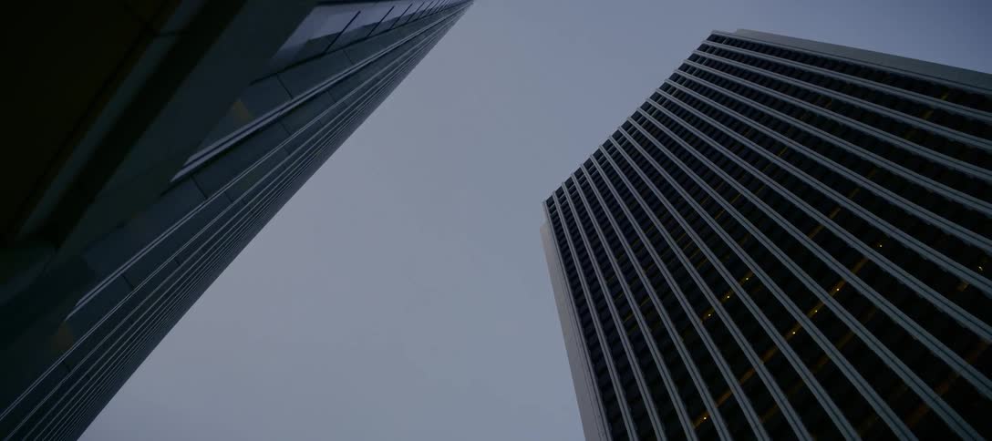 Looking up at two imposing modern skyscrapers from a low angle on an overcast day