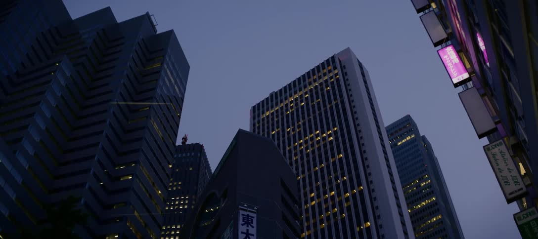 A low-angle shot tilts down from the twilight sky to reveal the towering skyscrapers of downtown Tokyo, Japan