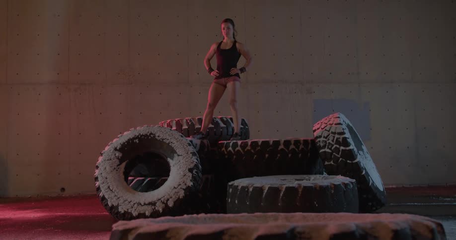 A female athlete is standing on a pile of large tires