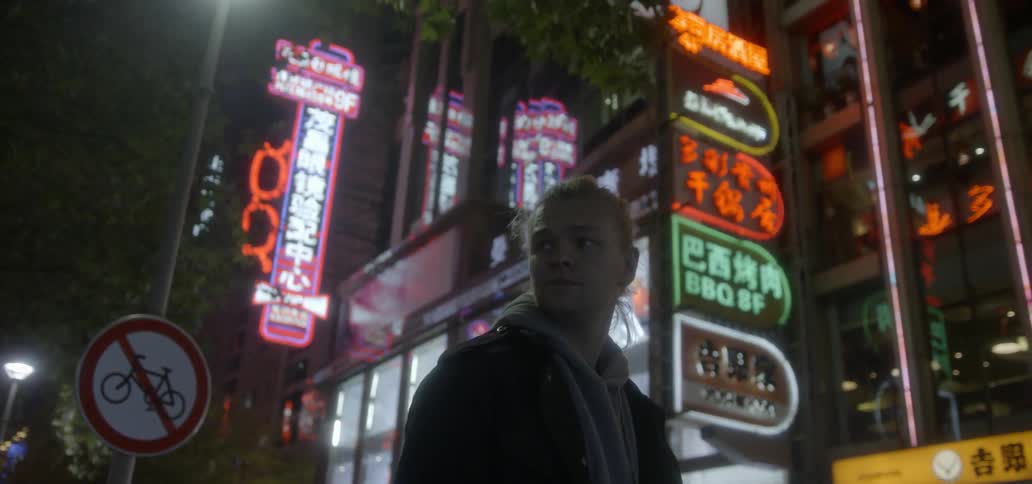 Man walks in a city at night with bright neon lights in the background