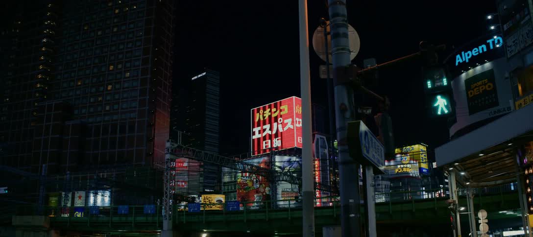 A slow pan reveals the vibrant neon signs and towering skyscrapers of a busy Japanese city street at night