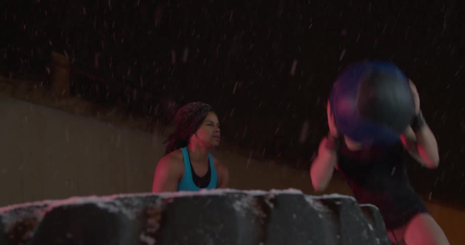 Two female athletes are working out at night while it snows