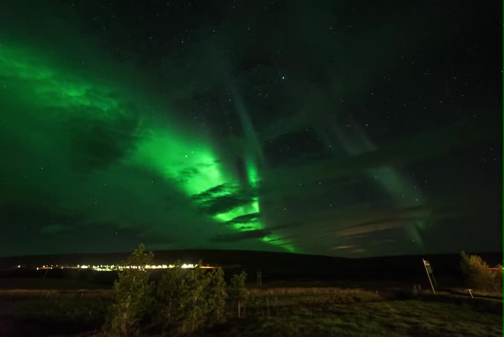 Northern lights glow in the dark night sky as cars travel below