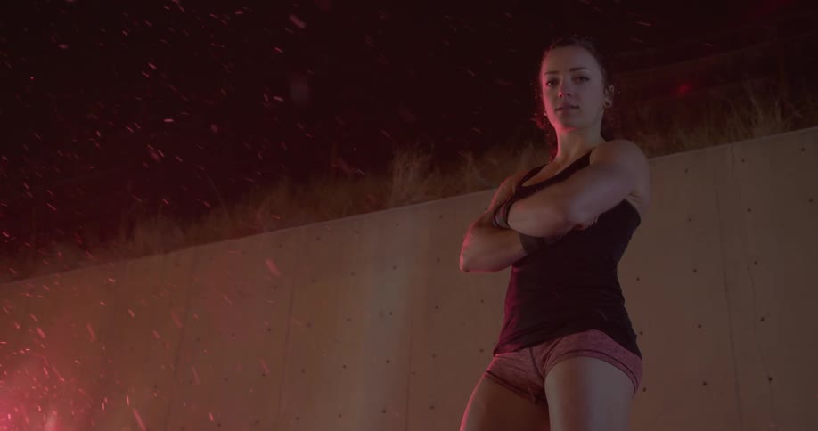 A woman crosses her arms while it snows outside at night