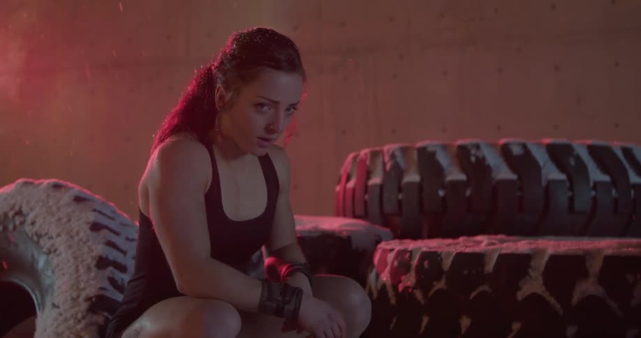 Woman sits and rests in front of large tires