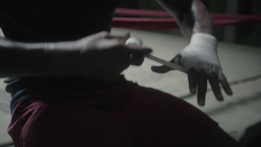 A boxer is wrapping his hand in tape