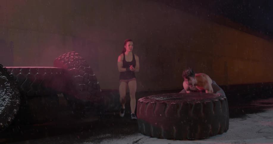A man flips a tire at night