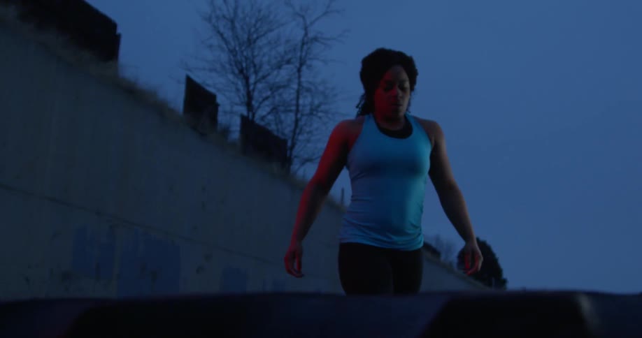 A woman in workout gear walks outside at night