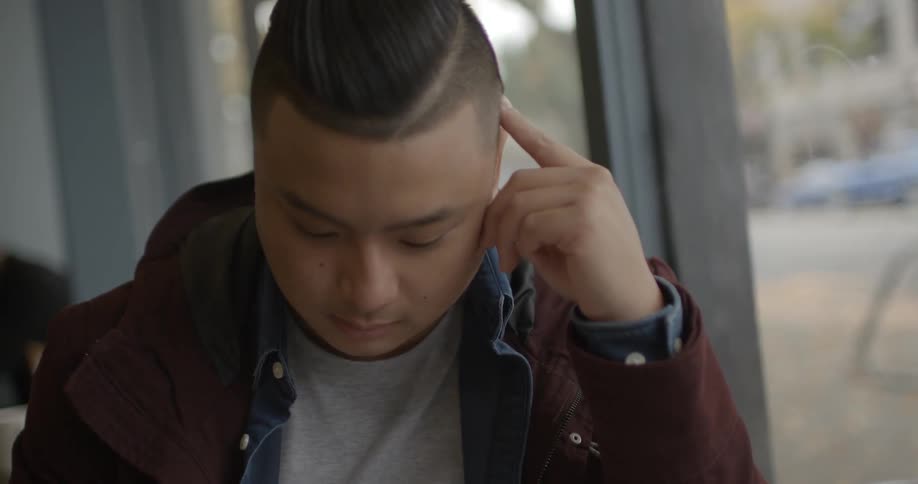 A man is sitting in a coffee shop concentrating on something