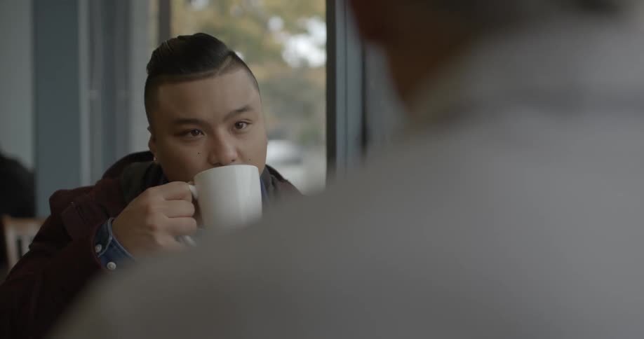 Two men chat over coffee in a coffee shop