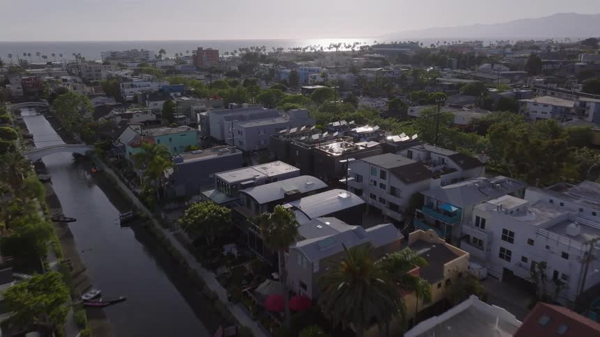 A stunning aerial shot flies over the Venice Canals and neighborhood towards the Pacific Ocean in Los Angeles, California