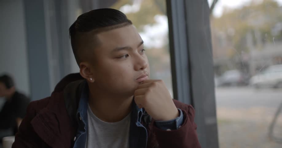 A man touches his chin looking out the window