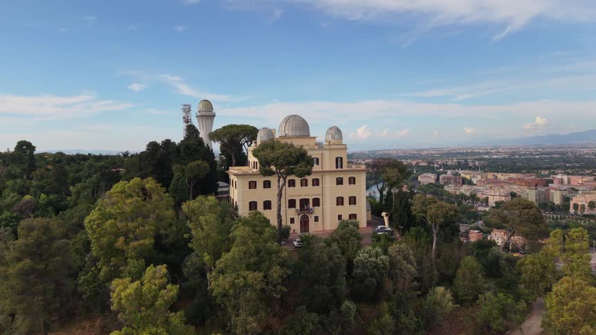 A majestic aerial shot circles the Astronomical Observatory of Rome on a lush green hill overlooking the city