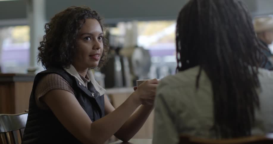 Two women talk while sitting in a coffee shop