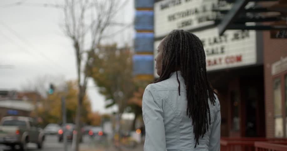 Woman walks down a city street on a cloudy day