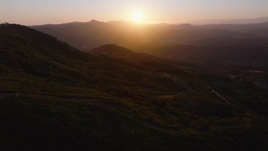 A majestic aerial flight over lush mountain ranges as the golden sun rises on the horizon