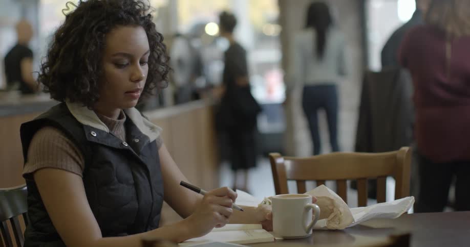 A woman sits in a cafe writing