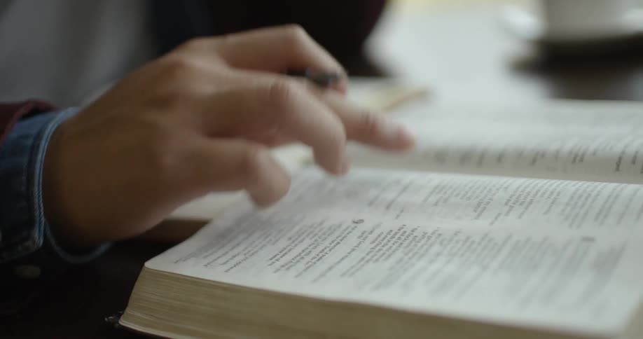 A finger passes over text in a book