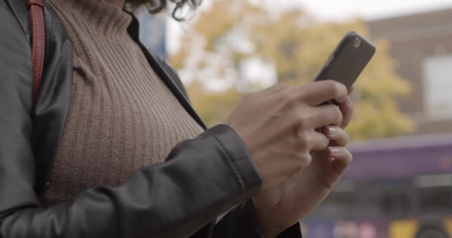 A woman looking at her phone outside