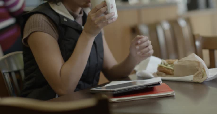 Woman drinking from a mug while using her tablet in a cafe