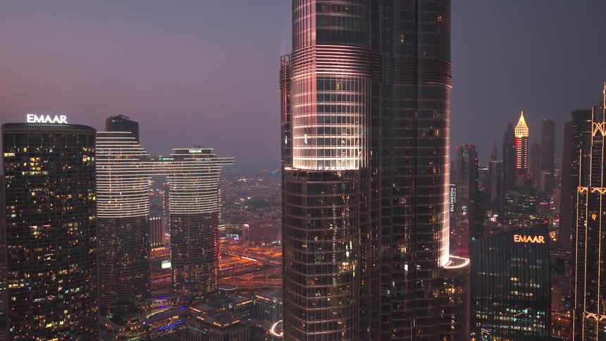 A stunning aerial view of the illuminated Burj Khalifa and the dazzling Dubai skyline at dusk, revealing the bustling cityscape below
