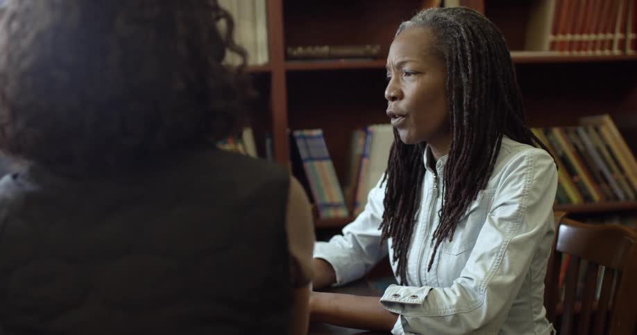 A woman is sitting at a table talking to others