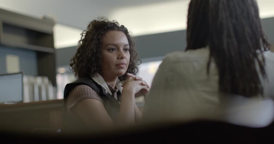 Two women are having a conversation in an open office area