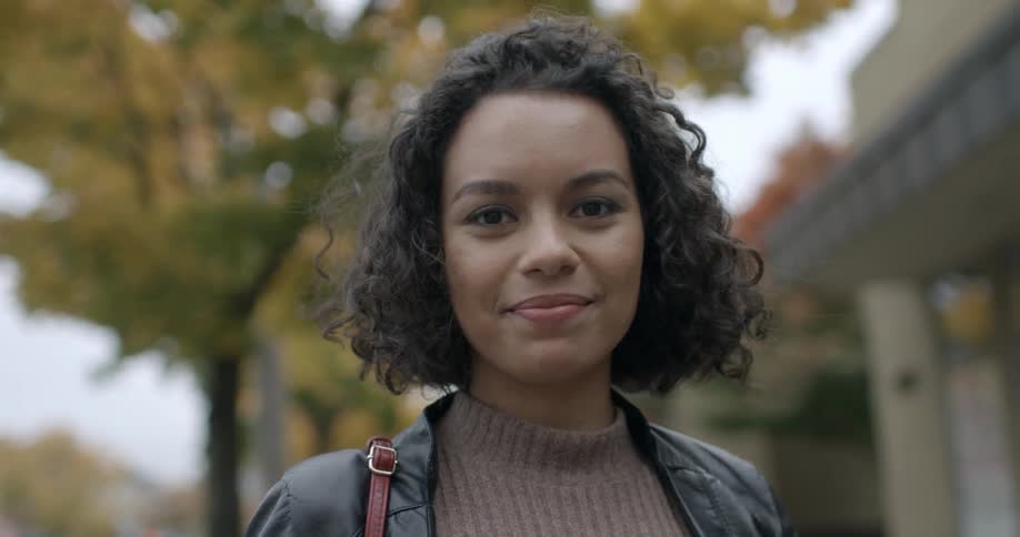 A woman is standing outside and smiling