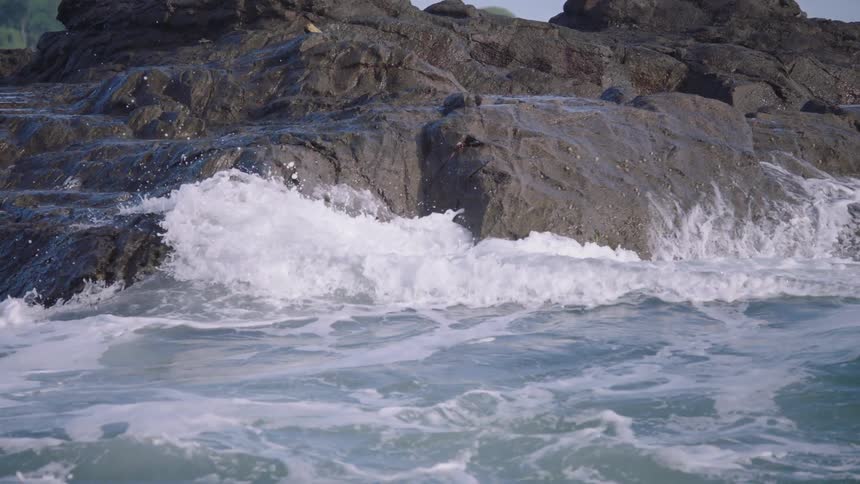 Close up of ocean waves breaking over a rocky shoreline in serene slow motion