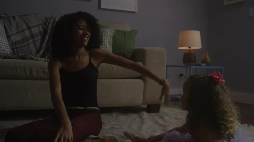 A woman and a child sit on the floor in a living room