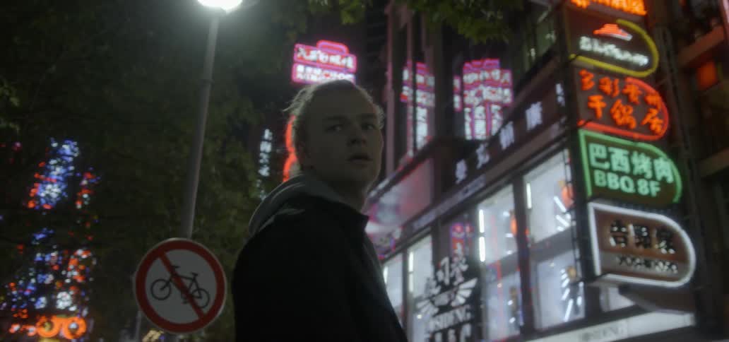 A man looks around at a brightly lit city at night