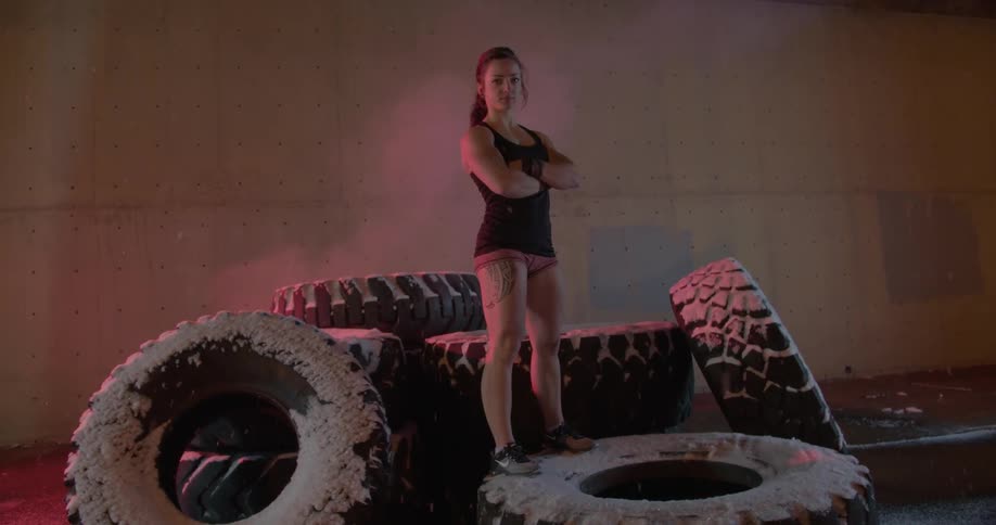 A woman stands on a pile of large tires while it snows