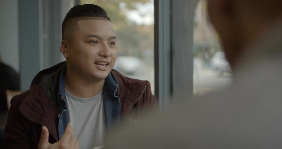 A couple of people sitting inside a diner talking and smiling